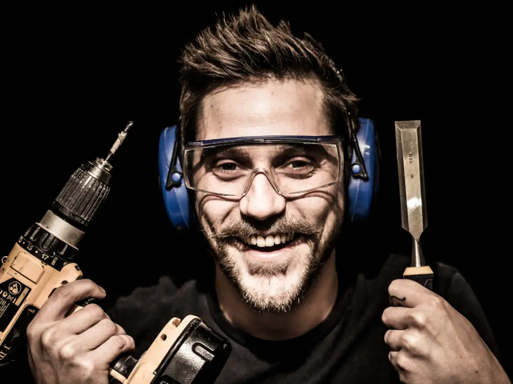 a man holding a drill and wearing goggles